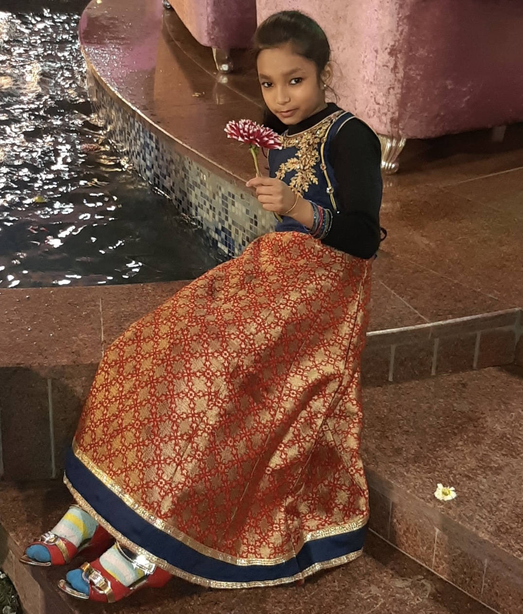 Tanya as a child in a festive lehenga holding a flower