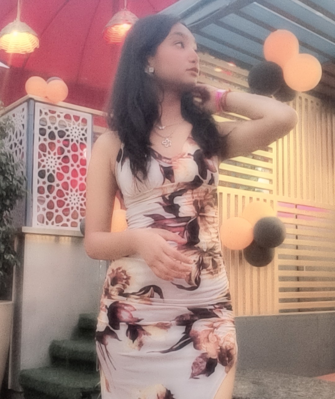 Tanya in a floral bodycon dress at a decorated rooftop lounge