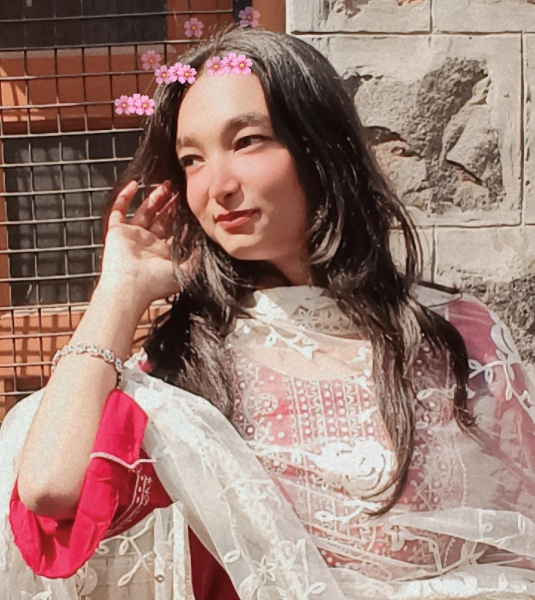 Tanya in a red and white traditional outfit with floral crown, smiling softly outdoors